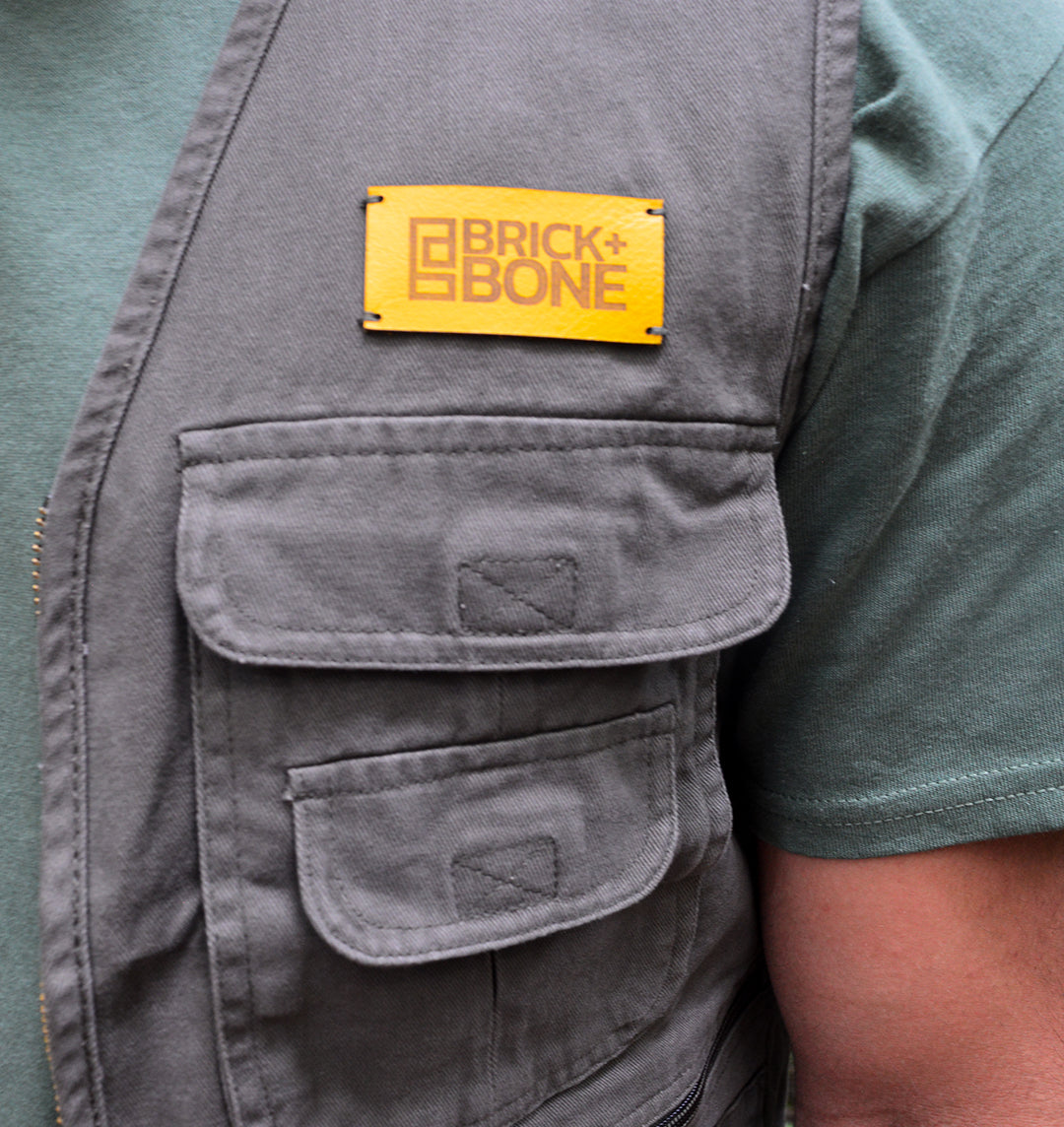 BRICK + BONE leather logo sewn onto a khaki utility vest