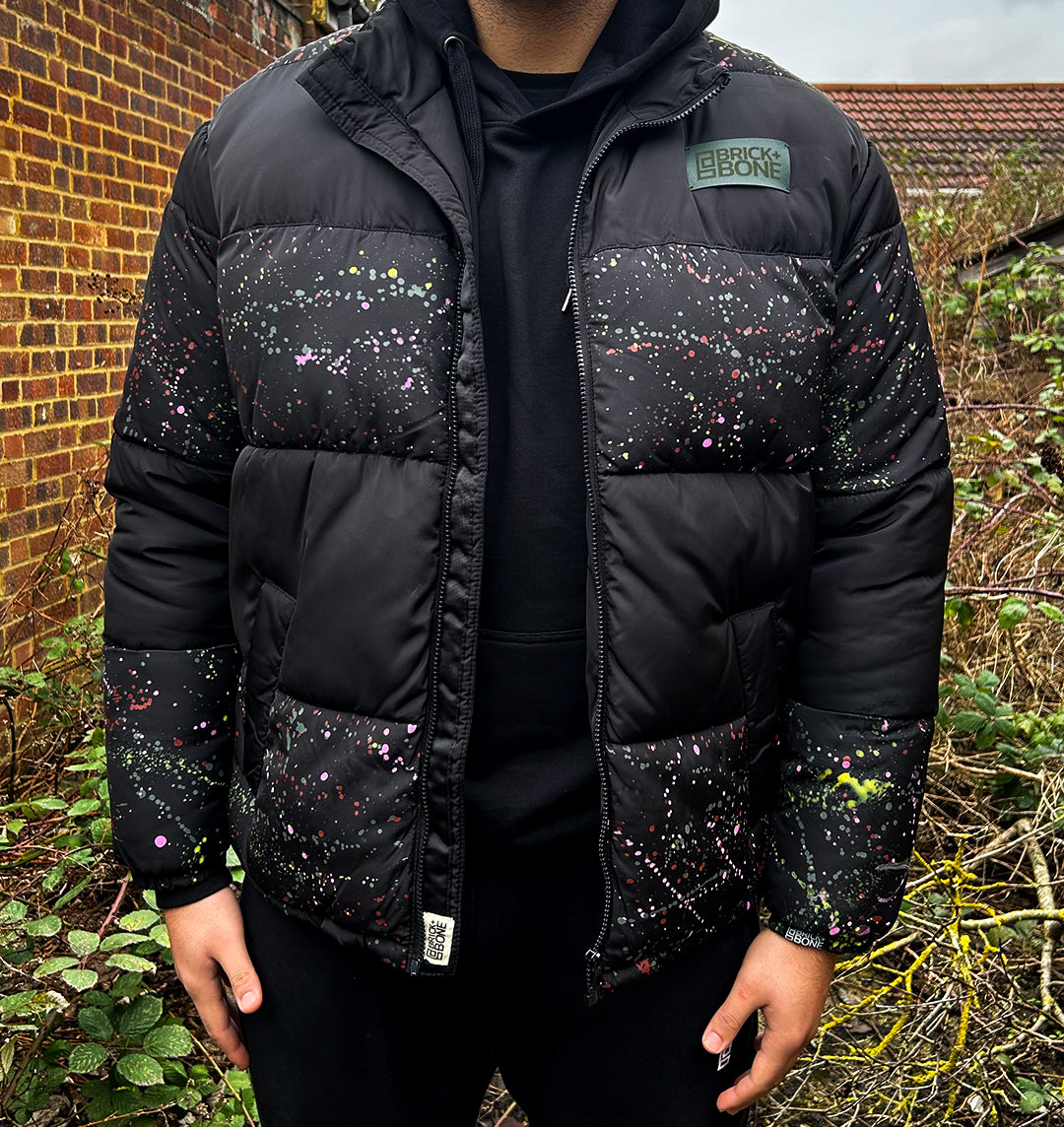 Upcycled puffer jacket with blocked out paint splatter across the front