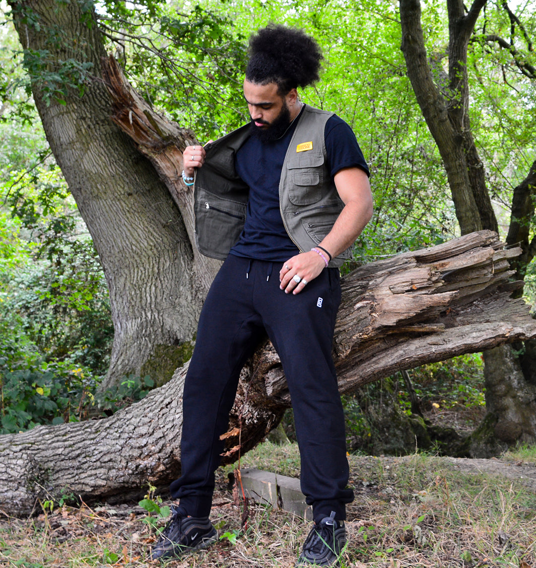 Streetwear with pockets. Man standing outside wearing the BRICK + BONE utility vest showing how many pockets it has